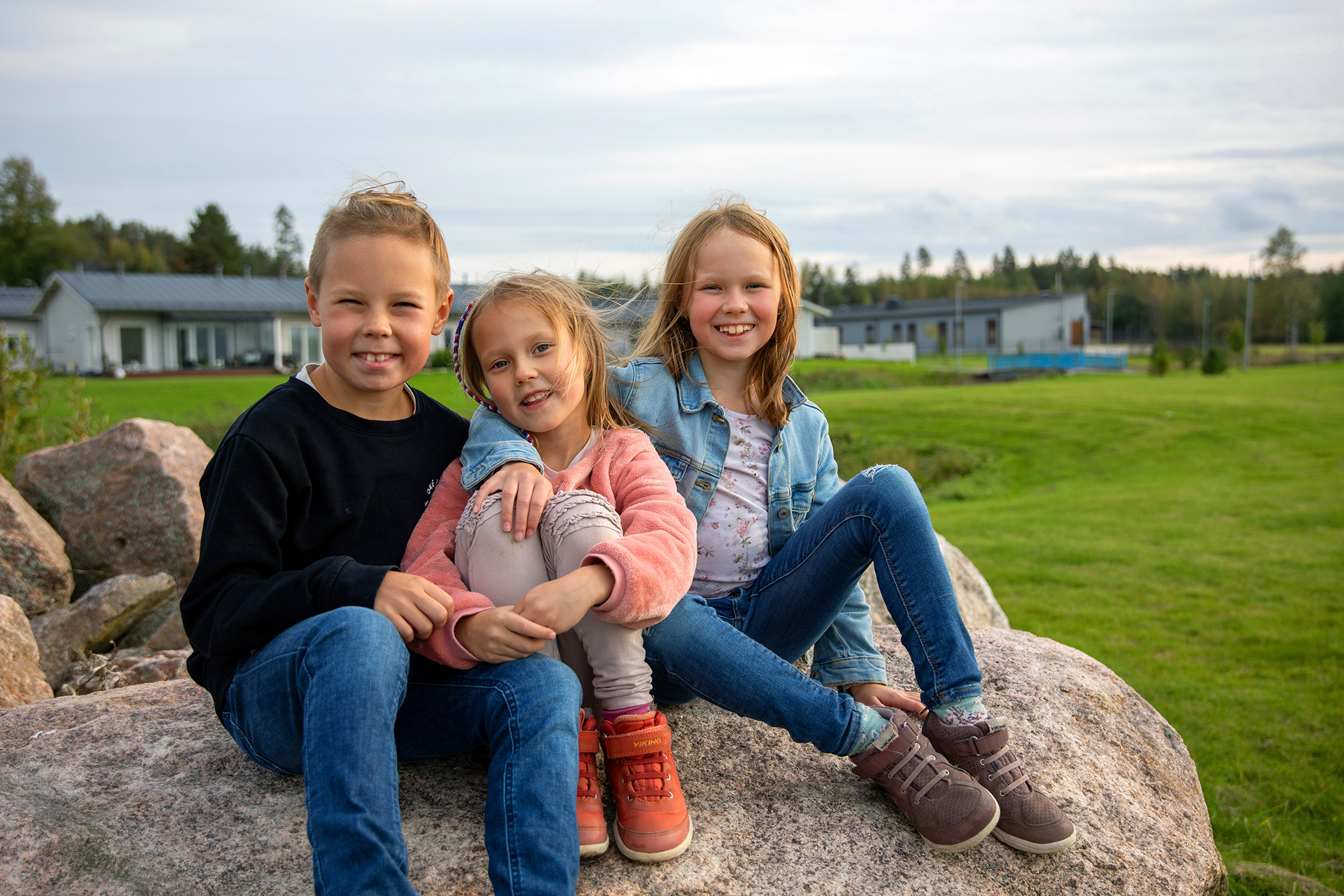 Kolme lasta istuu kivellä
