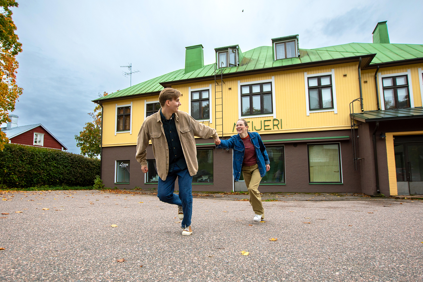Nuori pari juoksee vanhan rakennuksen edessä - kuva Kapina