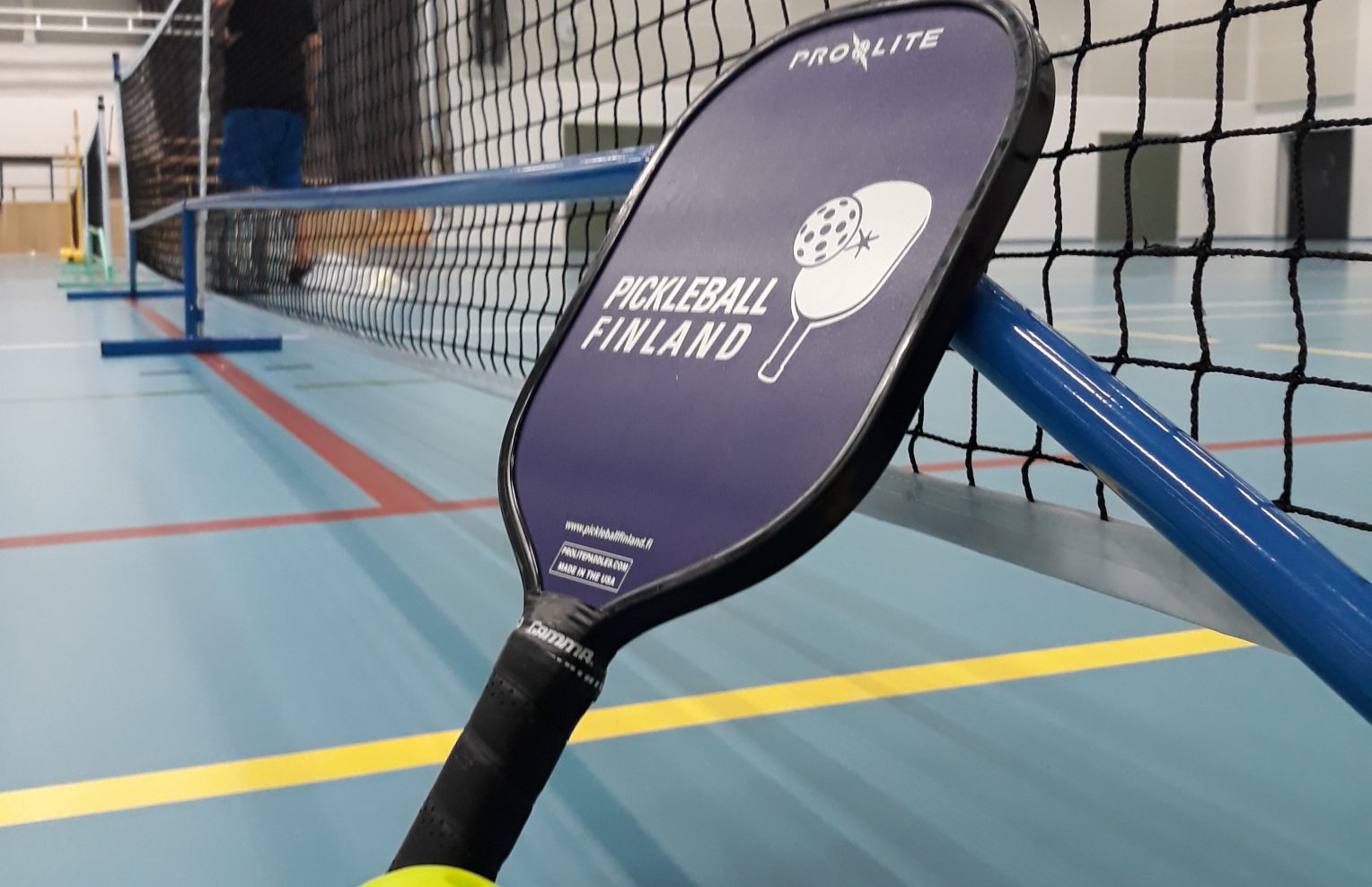Liikuntahallissa Pickleball pelivälineet eli maila, pallo ja verkko