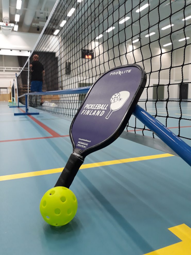 Liikuntahallissa Pickleball pelivälineet eli maila, pallo ja verkko