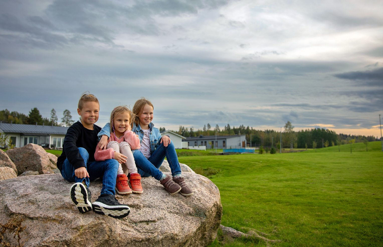 Kolme lasta istuu kivellä