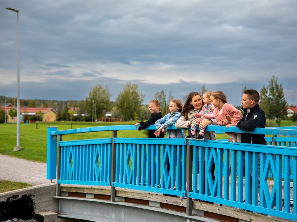 Seitsemän henkinen perhe nojailee sillan kaiteeseen iloisina.