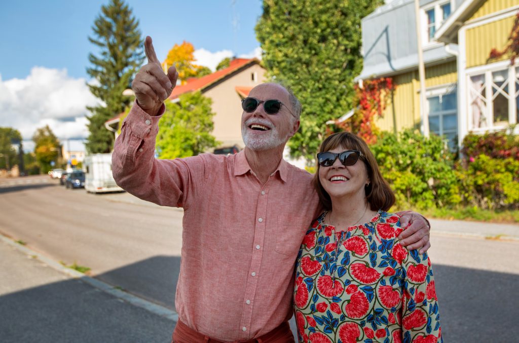 Vanhempi pariskunta katsovat ja osoittavat jotain ulkona hymyillen.