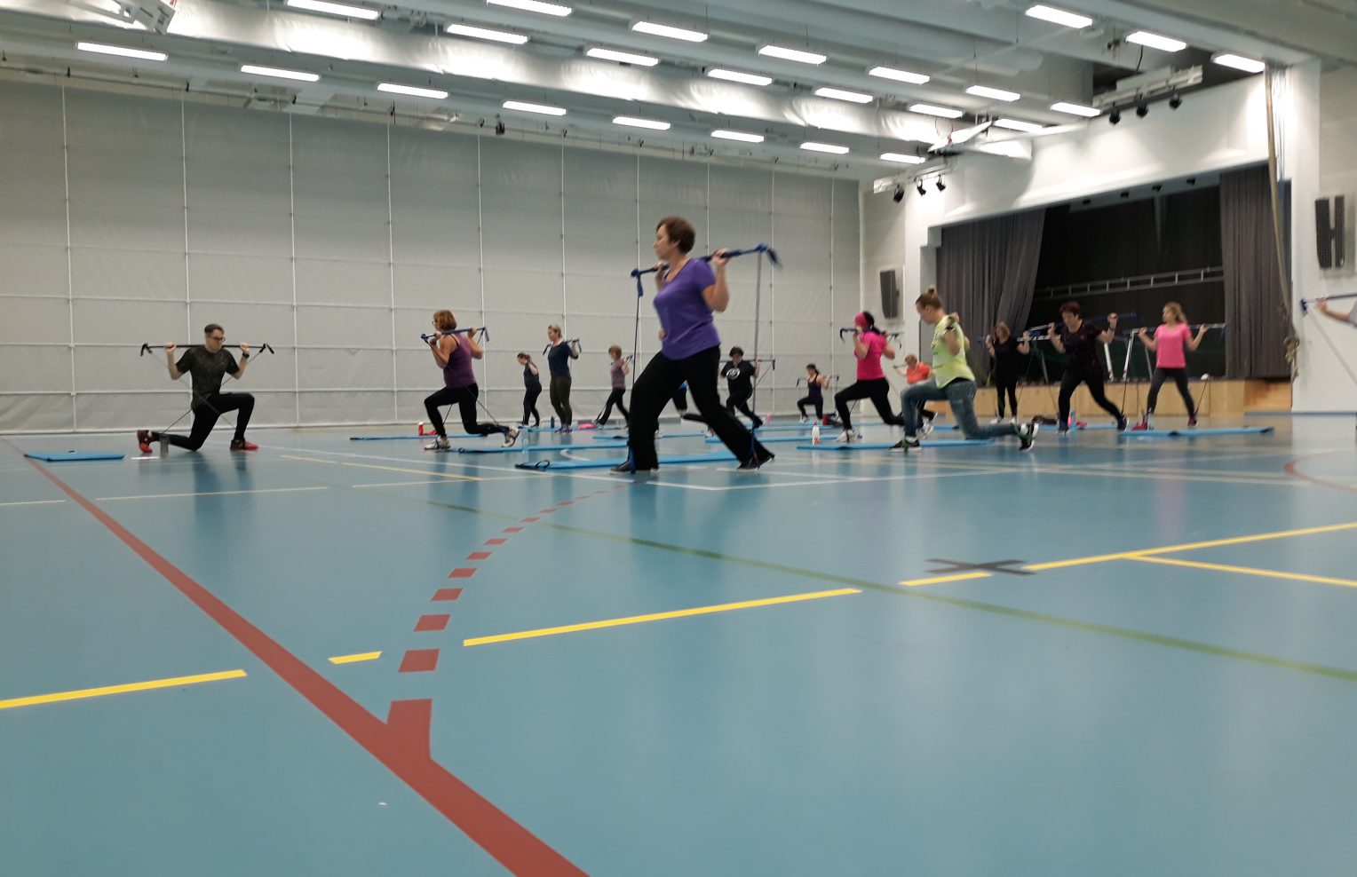 Ihmiset jumppaavat liikuntasalissa